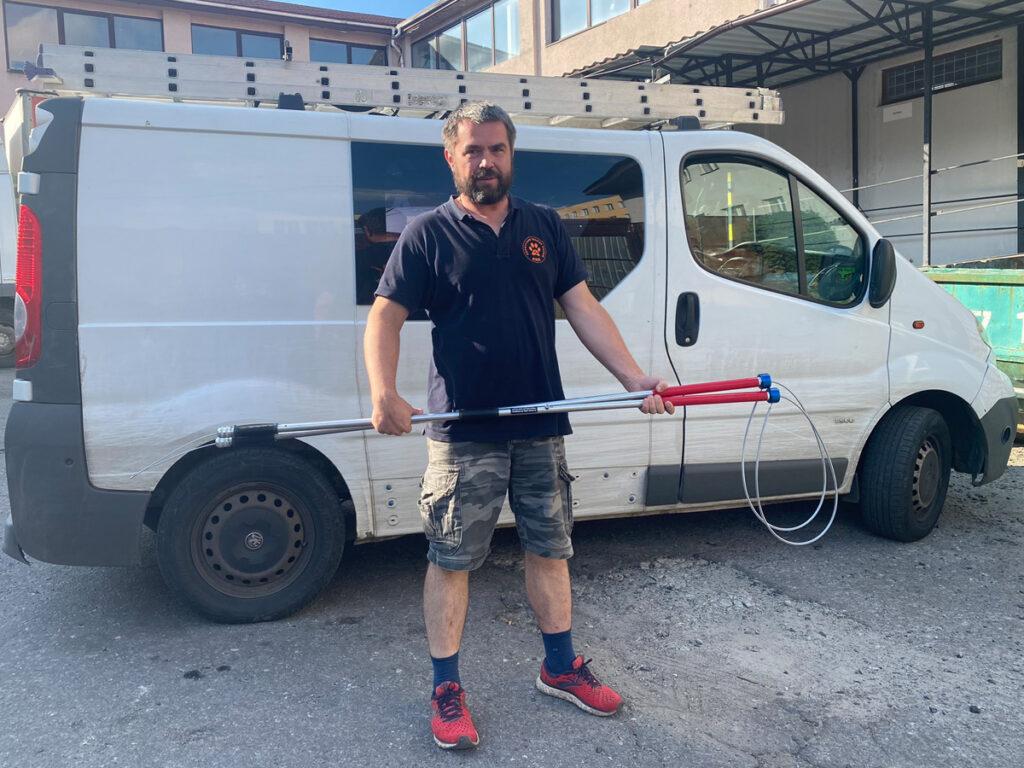 The war in Ukraine: How Naturewatch Foundation has been supporting animals in crisis 7 A man wearing a shirt with an ARK logo is standing in front of a white van. He is holding two humane dog catching poles, with large loops at the end.