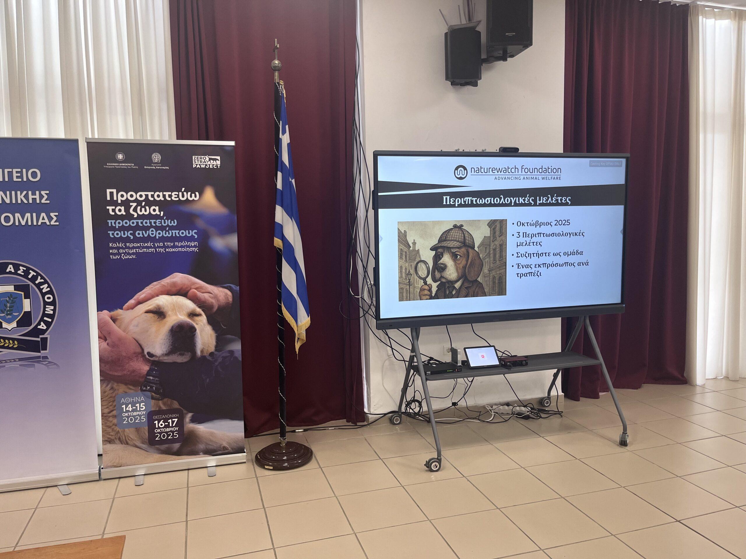 Zero to Hero: Police Training Across Greece for Safer Communities and Protected Animals 2 A presentation setup in a training room with banners from the Hellenic Police and Zero Stray Pawject. A screen displays a slide of case studies from Naturewatch Foundation.