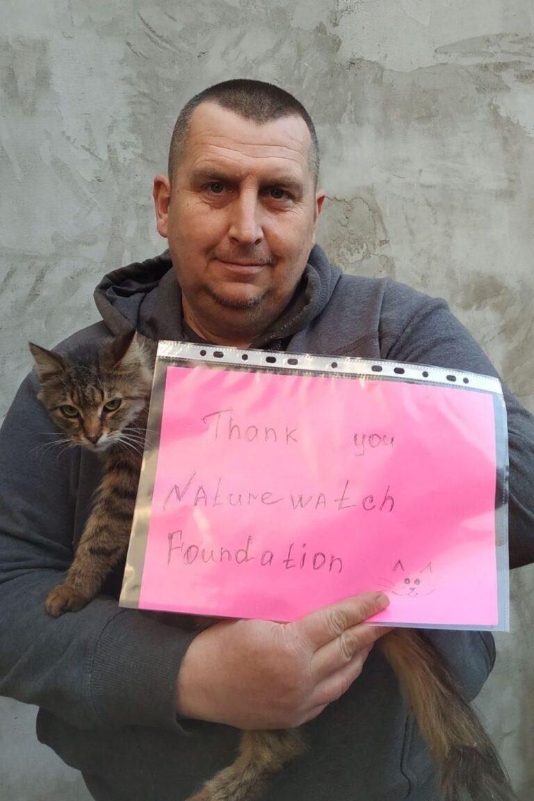 Your support 10 A smiling man in a grey hoodie holds a tabby cat and a pink sign that reads "Thank you Naturewatch Foundation" with a small cat doodle.