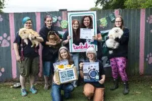Naturewatch Foundation staff and Teckels Animal Sanctuaries team members pose with rescued Pomeranians Pearl, Podge and Paula and Donate a Dinner campaign materials.