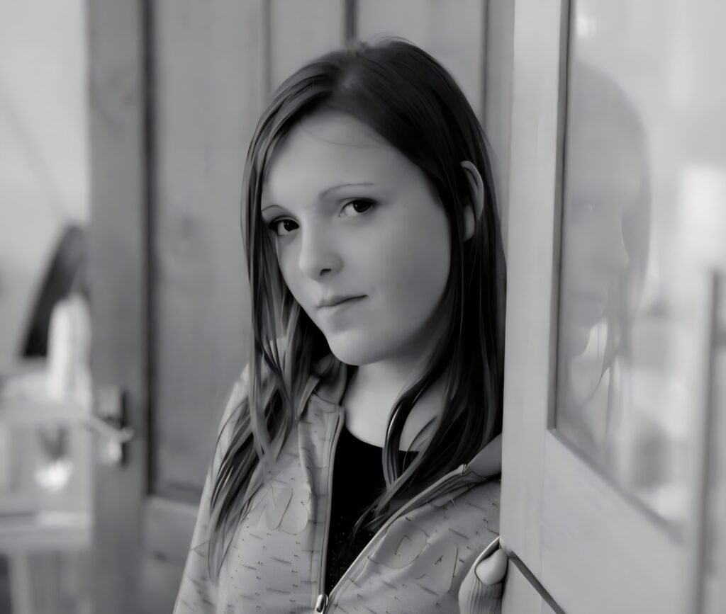 Why animal welfare belongs in public safety 1 Black and white, head and shoulders photograph of a young woman with long hair looking at the camera. Out of focus in the background is a wooden door that is slightly ajar